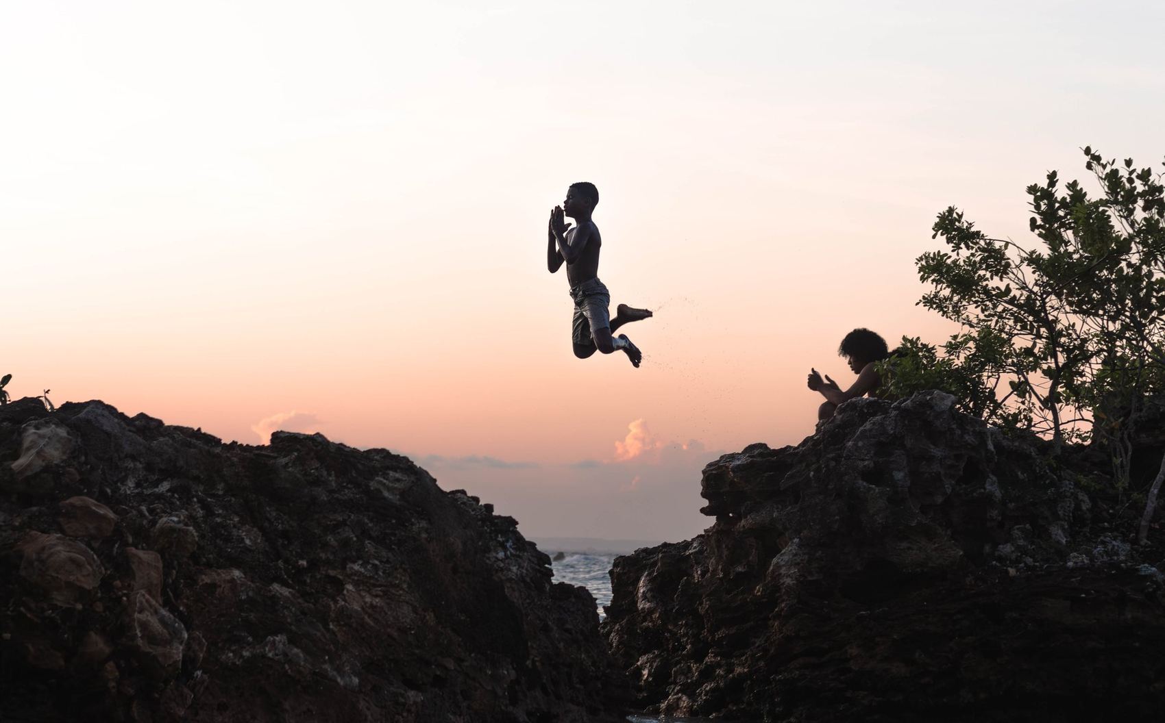 Meninos saltando de um costão ao fim da tarde