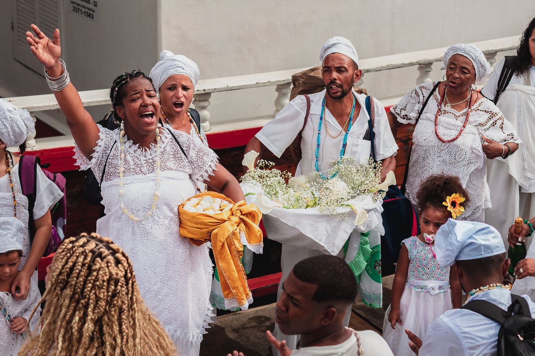 Mulheres de branco cantando com flores no colo